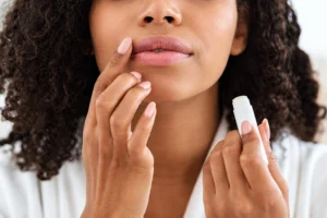 Woman applying lip balm while holding the tube, photo by BITCHSTIX